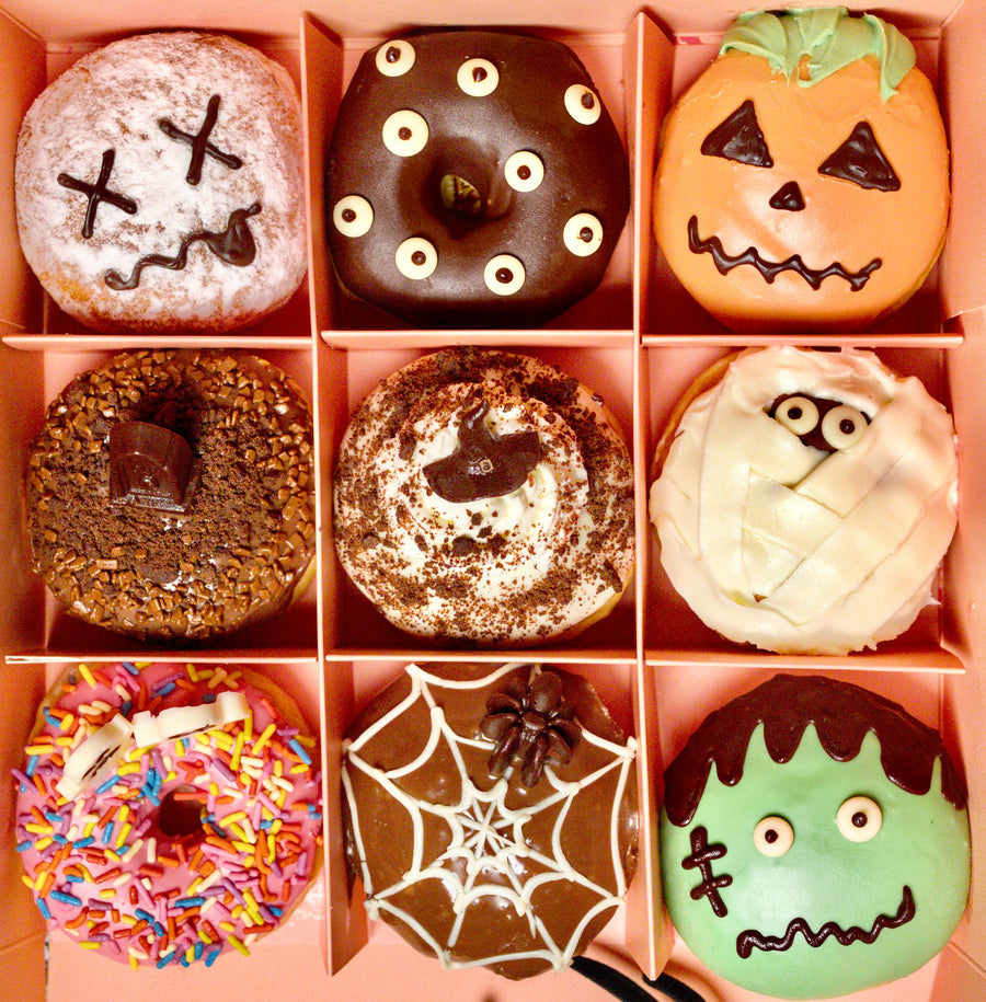 Let It Dough Halloween box of 9 doughnuts from above with skull, pumpkin, mummy, spider web and Frankenstein designs